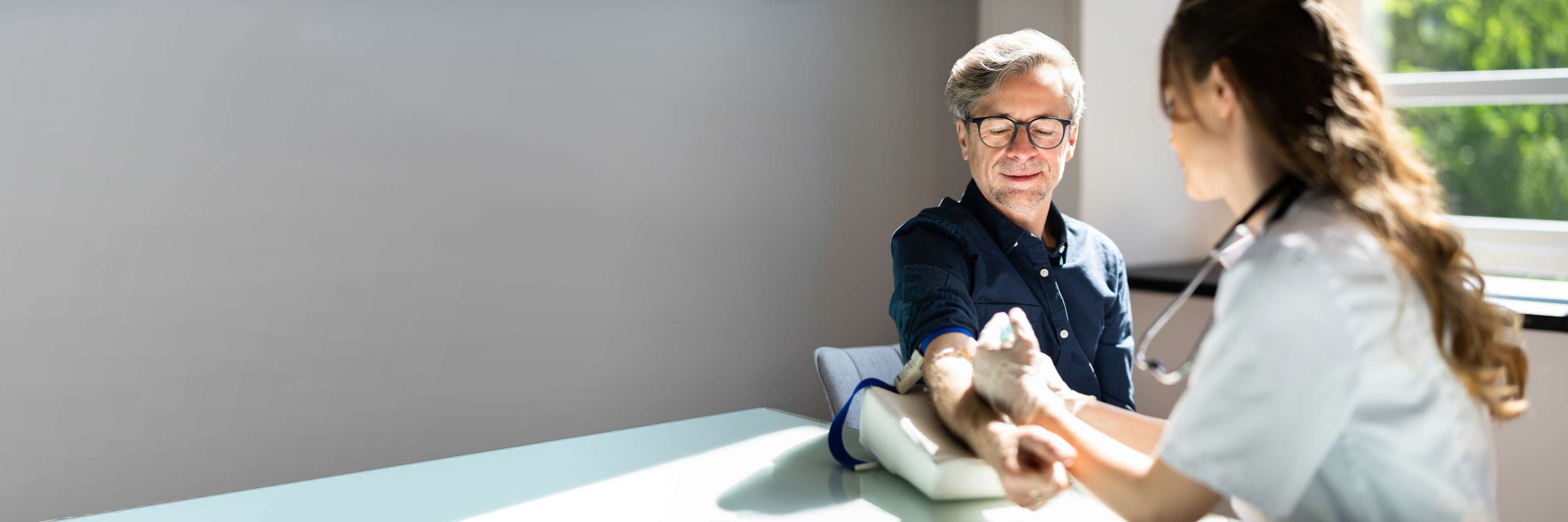 Technologiste médicale effectuant une prise de sang à domicile auprès d'un patient